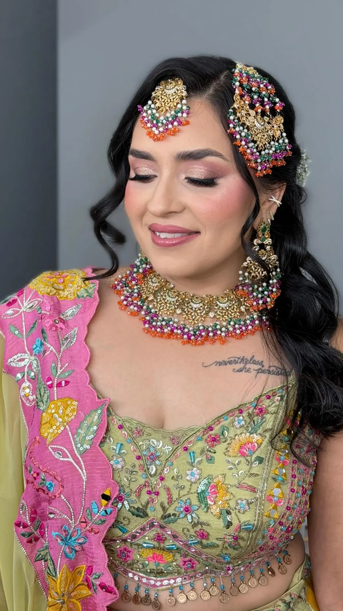 Bride in chartreuse with a pink embroidered dupatta, a multicoloured beaded choker and jhoomar, and soft curls.